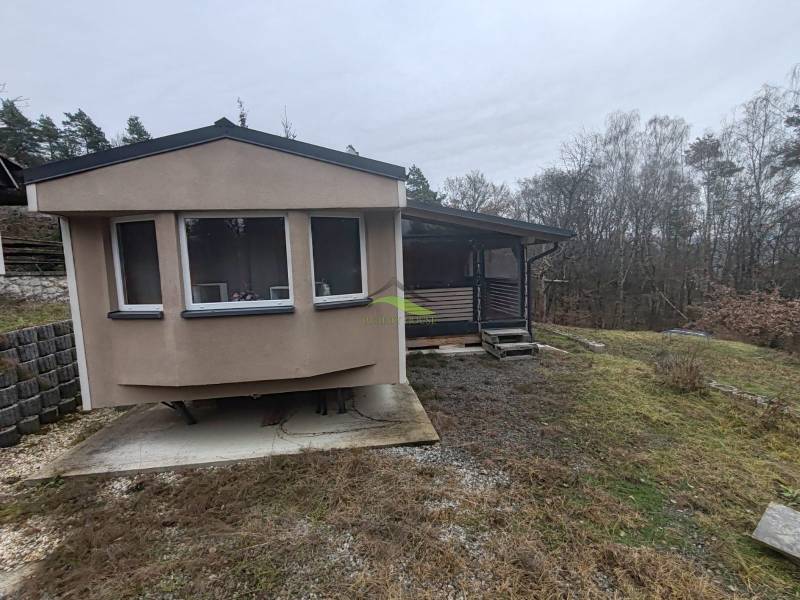 Pohoda pri vode, chata s výhľadom na Domašu - Chata na Hlavnej ulici v Novej Kelči obklopená stromami a mierne svahovitým terénom.