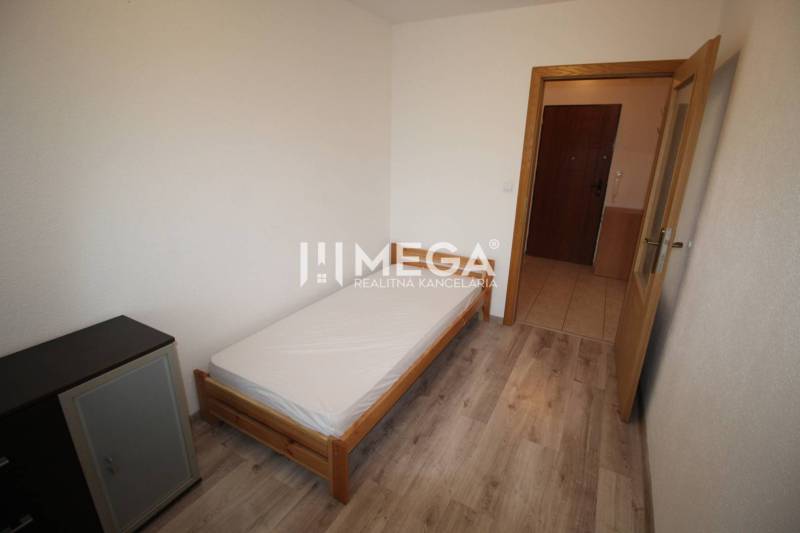 NA PRENÁJOM 1,5-IZB. BYT V MESTE HUMENNÉ - Spálňa s posteľou, komodou a podlahou s dreveným dekorom v 2-izbovom byte.