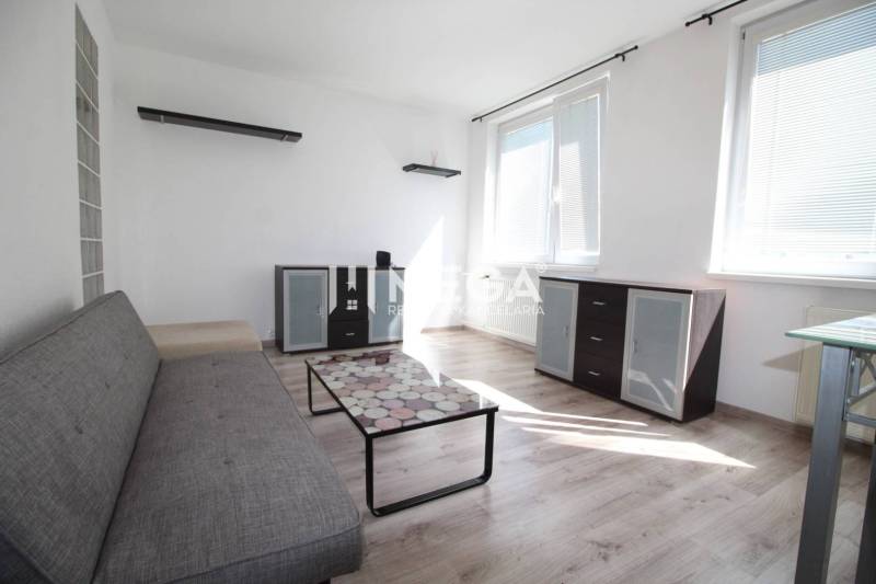 NA PRENÁJOM 1,5-IZB. BYT V MESTE HUMENNÉ - Obývačka v 2-izbovom byte s pohovkou, skleným stolíkom a podlahou s dreveným dekorom.