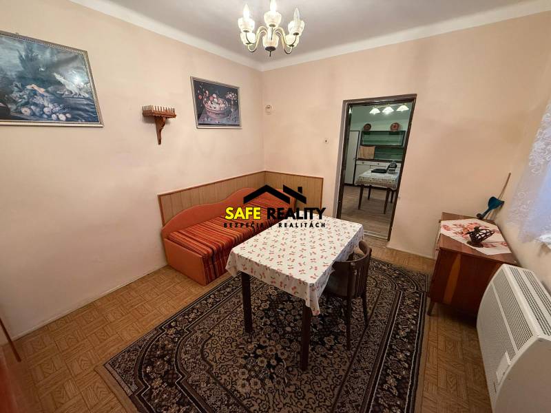 EXKLUZÍVNE Rodinný dom s veľkým potenciálom – Bešeňov - Jedáleň v rodinnom dome s kobercami, stolom a stoličkami, podlaha s dreveným dekorom.