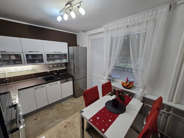 Predaj,trojizbový byt SNP, Holíč - Kuchyňa v 3-izbovom byte s bielym nábytkom, jedálenským stolom a podlahou s dreveným dekorom.