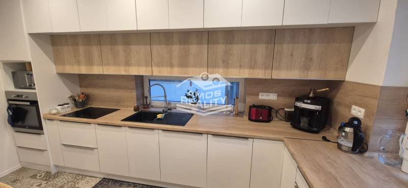 Na predaj 4 izbový RD v obci  Studienka, garáž, sauna, pozemok 719 m2 - Kuchyňa v rodinnom dome s bielymi skrinkami a pracovnou doskou s dreveným dekorom.