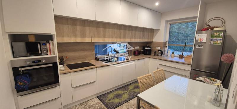 Na predaj 4 izbový RD v obci  Studienka, garáž, sauna, pozemok 719 m2 - Kuchyňa v rodinnom dome s bielymi skrinkami, spotrebiče s podlahou s dreveným dekorom.