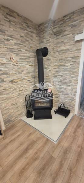 Na predaj 4 izbový RD v obci  Studienka, garáž, sauna, pozemok 719 m2 - Krb na drevo v rohu miestnosti s kamenným obkladom a podlahou s dreveným dekorom.