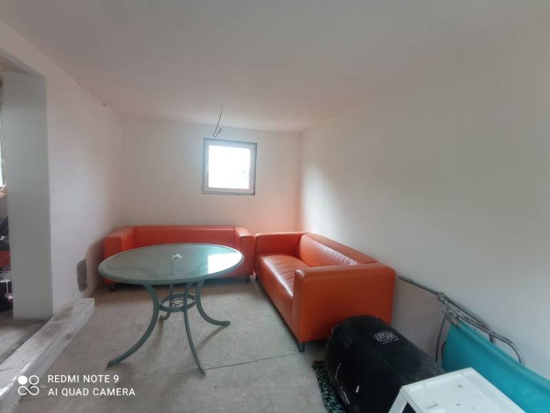 REZERVOVANÉ Chatka na krásnom mieste v kľudnom prostredí - Oranžové sedačky a okrúhly stôl dopĺňajú priestor v chate s bielymi stenami.