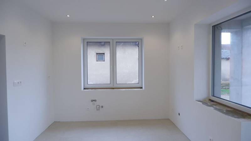 Ponúkame na predaj 4izb rodinný dom v štandarde v obci Radava - Prázdna miestnosť s bielymi stenami a veľkým oknom v rodinnom dome.