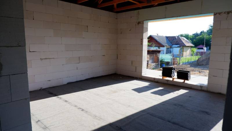 Ponúkame na predaj štvorizbový rodinný dom v obci Radava. - Výstavba rodinného domu v Radave s pohľadom na neomietnuté steny a okolitú krajinu.