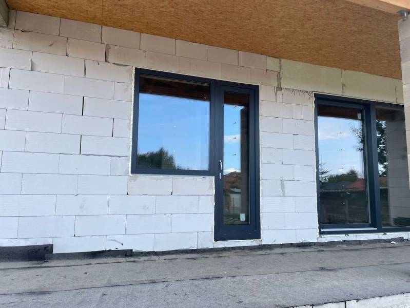 Ponúkame na predaj štvorizbový rodinný dom v obci Radava. - Nedokončená fasáda rodinného domu v Radave s plastovými dverami a oknami.