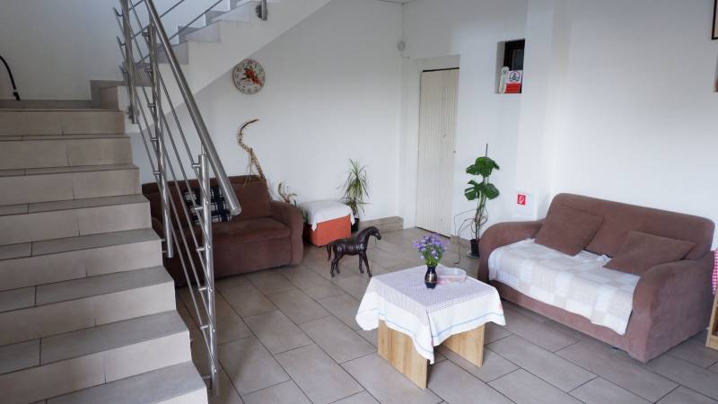 Ponúkame na predaj penzión v Poľnom Kesove - Interiér s pohovkou, stolom, rastlinami a schodmi v Hotely a penzióny.