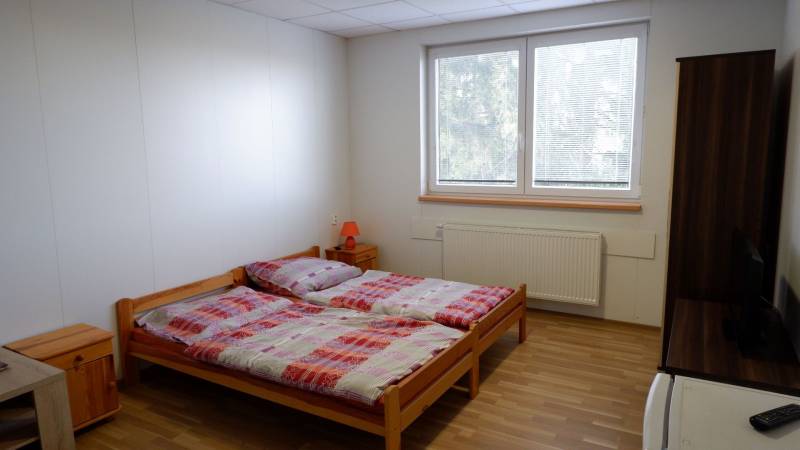 Ponúkame na predaj penzión v Poľnom Kesove - Pokoj s manželskou posteľou, podlahou s dreveným dekorom a moderným nábytkom v Hoteloch a penziónoch.