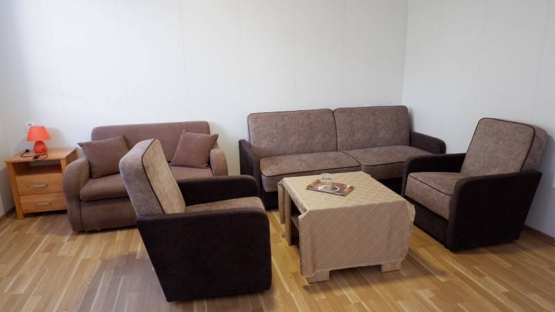 Ponúkame na predaj penzión v Poľnom Kesove - Obývacia izba s pohovkami, kreslami, stolíkom a podlahou s dreveným dekorom v Hoteloch a penziónoch.