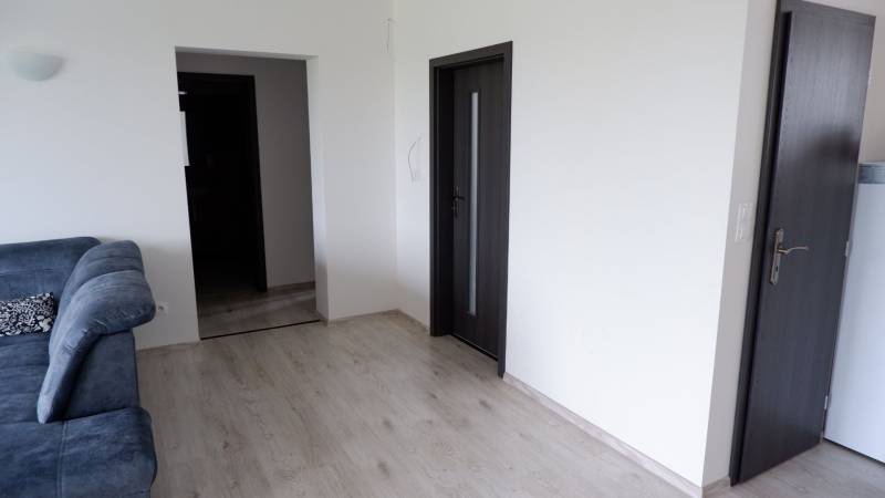 Ponúkame na predaj 3 izbový radový dom v obci Rastislavice. - Interiér rodinného domu s pohovkou, podlahou s dreveným dekorom a tmavými dverami.