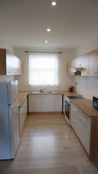 Ponúkame na predaj 3 izbový radový dom v obci Rastislavice. - Kuchyňa v rodinnom dome s bielymi skrinkami a podlahou s dreveným dekorom.