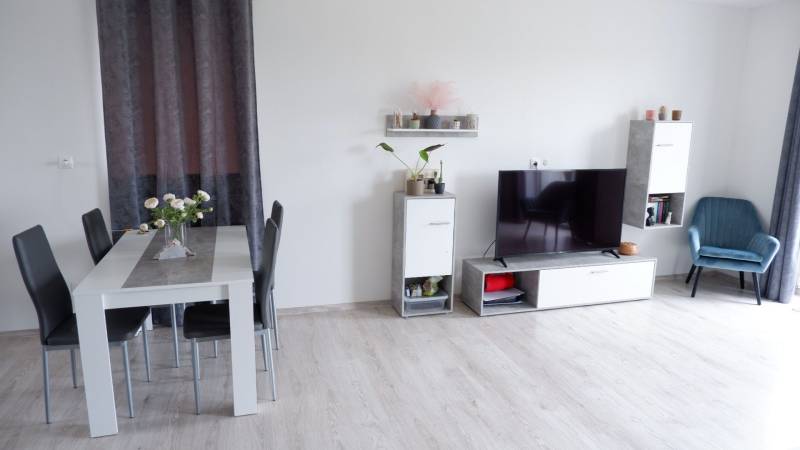 Ponúkame na predaj 3 izbový radový dom v obci Rastislavice. - Interiér rodinného domu s jedálenským stolom, televízorom a podlahou s dreveným dekorom.