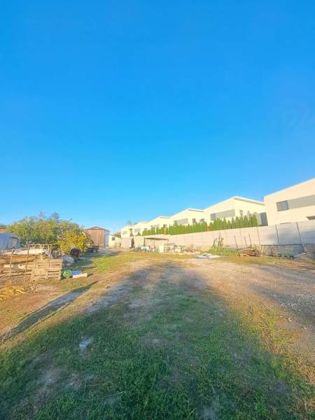 Rodinný dom s veľkým pozemkom v Kolárove –  na bývanie, podnikanie - Pohľad na rodinné domy v Kolárove s priľahlým priestranstvom a jasnou modrou oblohou.