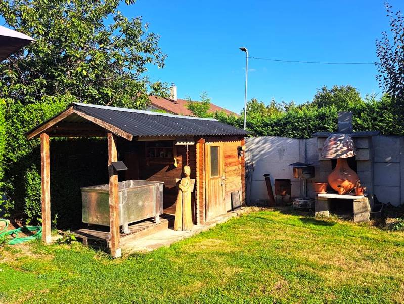 Domov, kde si vytvoríte vlastný príbeh – rodinný dom na predaj, Neded - Záhrada rodinného domu v Nedede s dreveným domčekom a vonkajším kozubom.