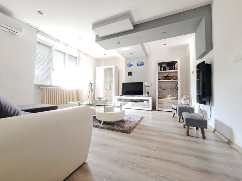 Domov, kde si vytvoríte vlastný príbeh – rodinný dom na predaj, Neded - Obývacia izba v rodinnom dome s podlahou s dreveným dekorom a pohovkou.