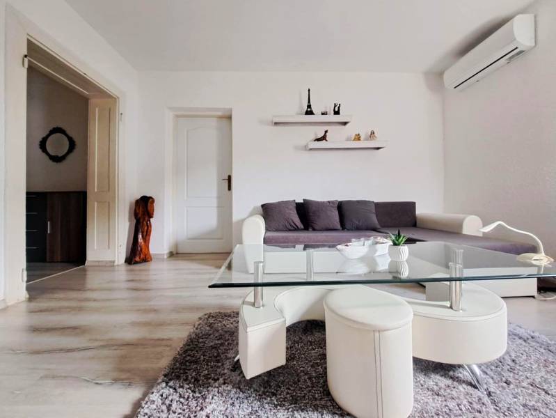 Domov, kde si vytvoríte vlastný príbeh – rodinný dom na predaj, Neded - Obývačka v rodinnom dome s pohovkou, skleneným stolíkom a podlahou s dreveným dekorom.