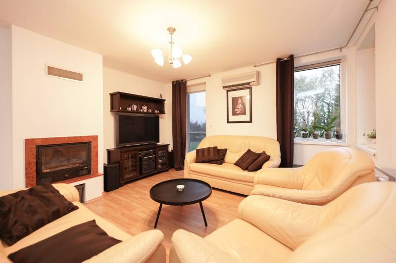 ViNi real / TOP PONUKA! Moderný 4-izb. bungalov s garážou, KVETOSLAVOV - Obývacia izba v rodinnom dome s krbom, koženými sedačkami a podlahou s dreveným dekorom.