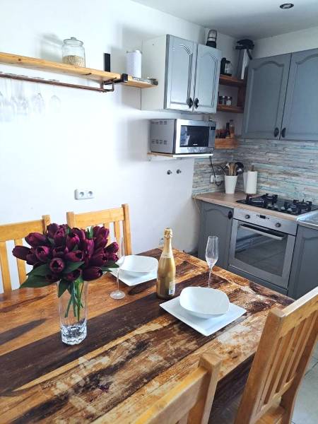 Exkluzívne na predaj 5 izbový rodinný dom - Kuchyňa v rodinnom dome s dreveným stolom, kvetmi, šampanským a kuchynskou linkou.