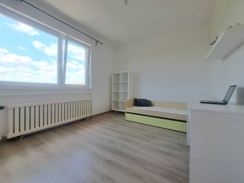 Exkluzívne na predaj 5 izbový rodinný dom - Svetlá izba s poličkami, rozkladacou posteľou a oknom v rodinnom dome, podlaha s dreveným dekorom.