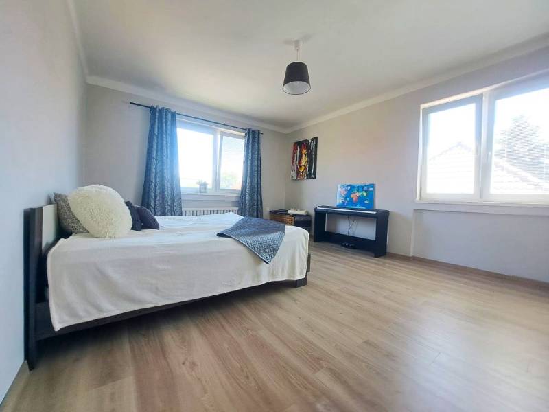 Exkluzívne na predaj 5 izbový rodinný dom - Izba s posteľou, dvoma oknami, klavírom a podlahou s dreveným dekorom v rodinnom dome.