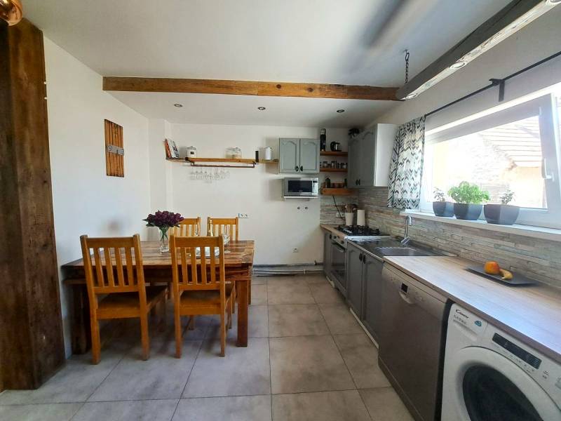 Exkluzívne na predaj 5 izbový rodinný dom - Kuchyňa v rodinnom dome s dreveným stropným trámom a sériou drevených stoličiek.