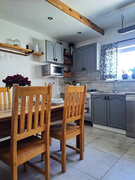 Exkluzívne na predaj 5 izbový rodinný dom - Kuchyňa v rodinnom dome s dreveným stolom, stoličkami a sivými skrinkami.