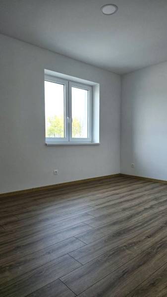 Moderný nízkoenergetický 4-izbový rodinný dom, Cífer – Karlov Dvor - Izba v rodinnom dome s podlahou s dreveným dekorom a bielymi stenami.