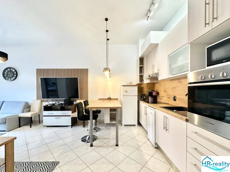 Trogir, Čiovo – pekný, zariadený apartmán len 150m od pláže - Interiér rekreačného apartmánu s kuchynskou linkou, jedálenským stolom a televíziou na stene.