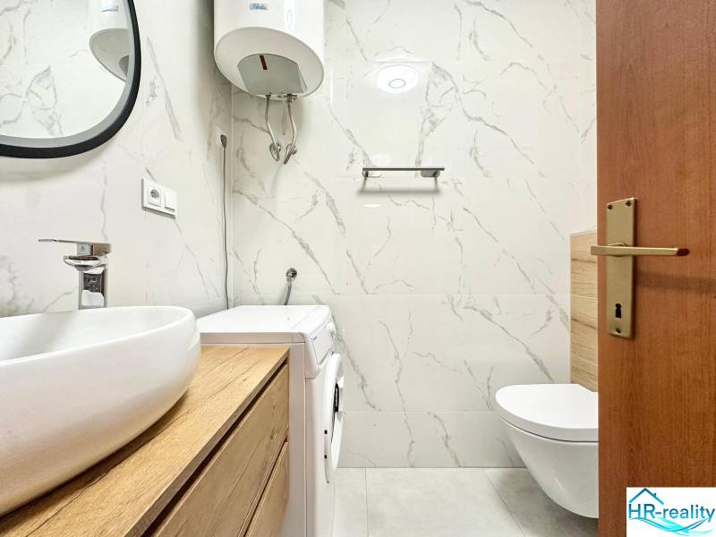 Trogir, Čiovo – pekný, zariadený apartmán len 150m od pláže - Kúpeľňa v rekreačnom apartmáne s toaletou, práčkou a umývadlom na drevenom dekore.