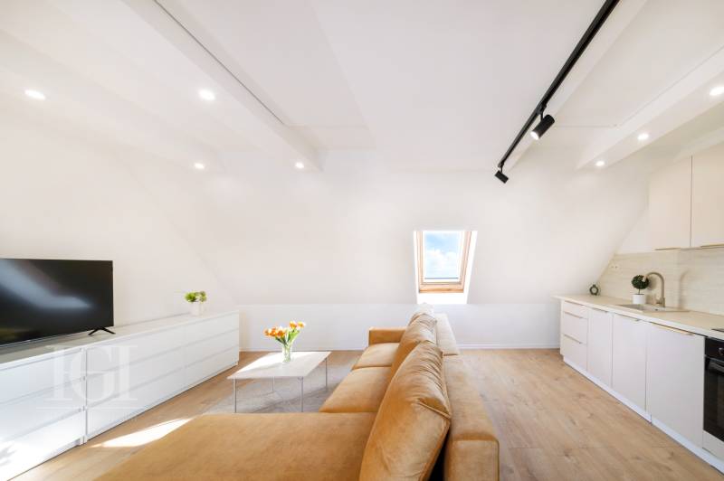  REZERVOVANY-PRENAJOM | NOVÝ 2 i. podkrovný byt v novostavbe - Svetlá obývacia izba s béžovou pohovkou, podlahou s dreveným dekorom a strešným oknom.