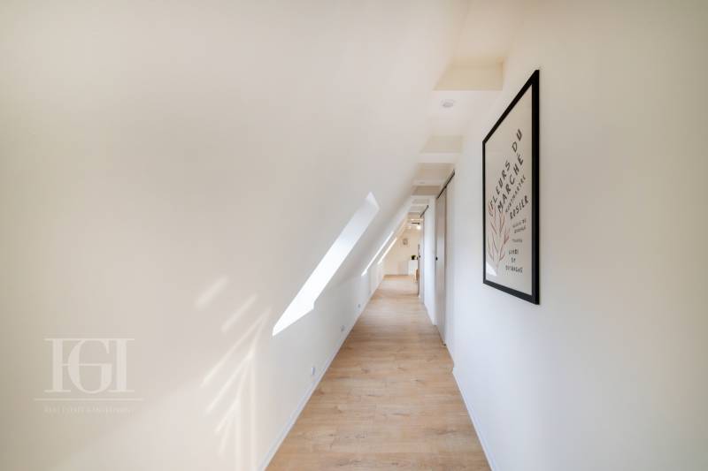  REZERVOVANY-PRENAJOM | NOVÝ 2 i. podkrovný byt v novostavbe - Chodba v 2-izbovom byte s podlahou s dreveným dekorom, strešným oknom a obrazom na stene.