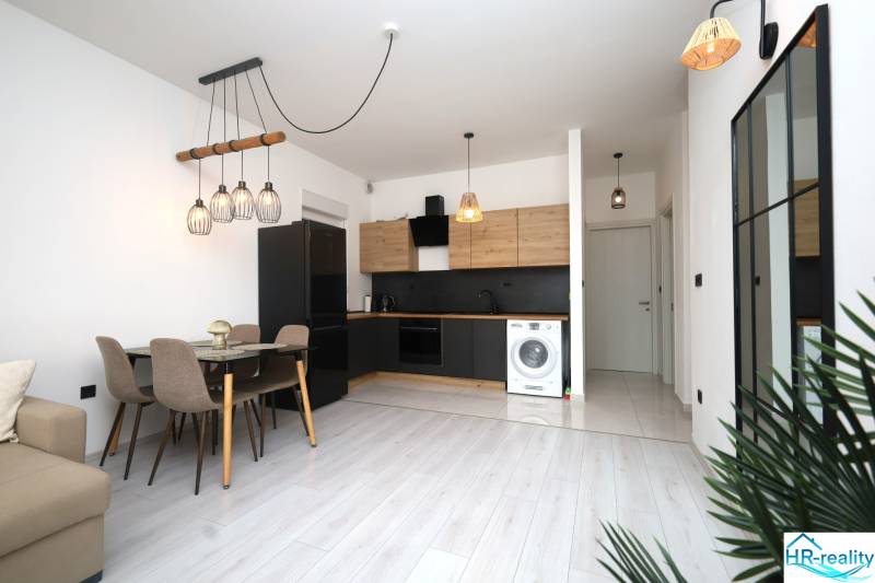 Vodice – novo zrekonštruovaný dvojspálňový apartmán s výhľadom na more - Kuchyňa v rekreačnom apartmáne s jedálenským stolom a podlahou s dreveným dekorom.