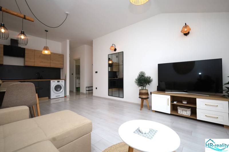 Vodice – novo zrekonštruovaný dvojspálňový apartmán s výhľadom na more - Obývacia izba rekreačného apartmánu so sedačkou, TV a kuchynským kútom.