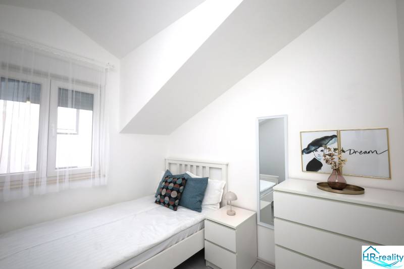 Vodice – novo zrekonštruovaný dvojspálňový apartmán s výhľadom na more - Svetlá spálňa v rekreačnom apartmáne s posteľou, nočným stolíkom a komodou.