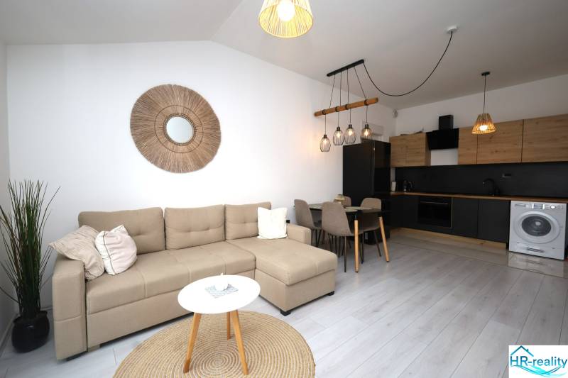 Vodice – novo zrekonštruovaný dvojspálňový apartmán s výhľadom na more - Obývačka v rekreačnom apartmáne s kuchyňou, pohovkou a dekoratívnym prvkami na stene.