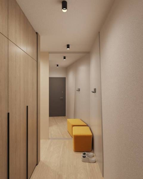 Prémiové byty s vysokým investičným potenciálom - Interiér budovy s podlahou s dreveným dekorom, šatník, zrkadlo a žlté sedenie.