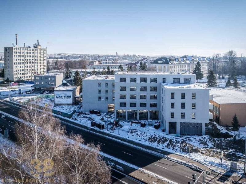 Prémiové byty s vysokým investičným potenciálom - Zimná panoráma Popradu s budovami na zasneženej ulici.