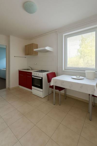 Znížená cena  4-izbový rodinný dom s veľkým pozemkom len 5min od Šale - Kuchyňa s červenou skrinkou, stolom a dvoma stoličkami v rodinnom dome.