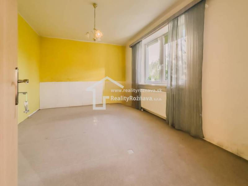 Rodinný dom vo vyhľadávanej obci Betliar. - Izba v rodinnom dome s veľkým oknom, žlté steny a závesy.