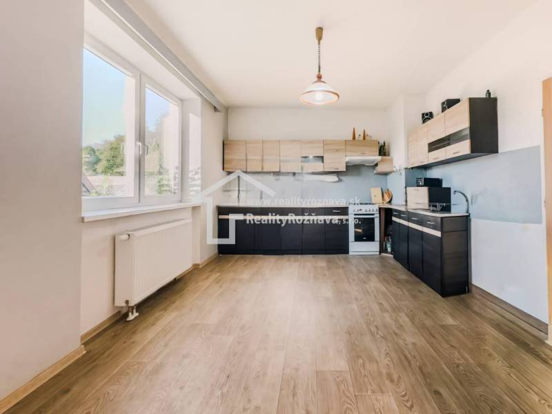 Rodinný dom vo vyhľadávanej obci Betliar. - Kuchyňa v rodinnom dome s podlahou s dreveným dekorom a veľkým oknom.