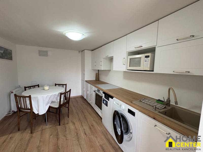 NA PRENÁJOM krásny 1 izbový apartmán so záhradou v srdci Komárna - Kuchyňa v 1-izbovom byte s podlahou s dreveným dekorom a jedálenským stolom.