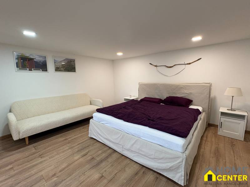 NA PRENÁJOM krásny 1 izbový apartmán so záhradou v srdci Komárna - Spálňa v 1-izbovom byte s pohovkou, posteľou a podlahou s dreveným dekorom.