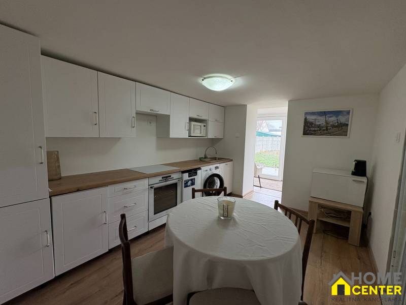 NA PRENÁJOM krásny 1 izbový apartmán so záhradou v srdci Komárna - Kuchyňa v 1-izbovom byte s podlahou s dreveným dekorom a jedálenským stolom.