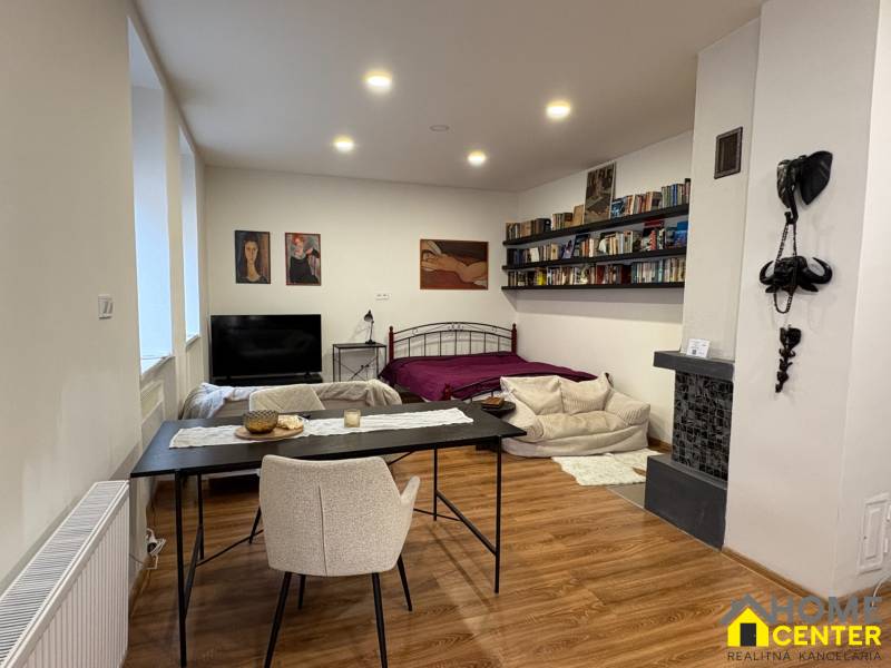 EXKLUZÍVNE na prenájom apartmán s nádychom afrického štýlu v centre KN - Interiér 1-izbového bytu s podlahou s dreveným dekorom, posteľou a jedálenským stolom.