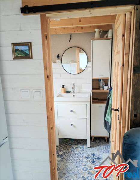 Tiny house - malý domček - Kúpeľňa v rodinnom dome s okrúhlym zrkadlom a vzorovanou dlažbou.