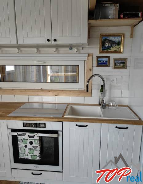 Tiny house - malý domček - Kuchynská linka v rodinnom dome s bielymi skrinkami, umývadlom a vstavanou rúrou.