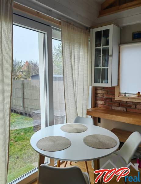 Tiny house - malý domček - Jedálenský kút v rodinnom dome s podlahou s dreveným dekorom, tehlovou stenou a veľkými oknami.