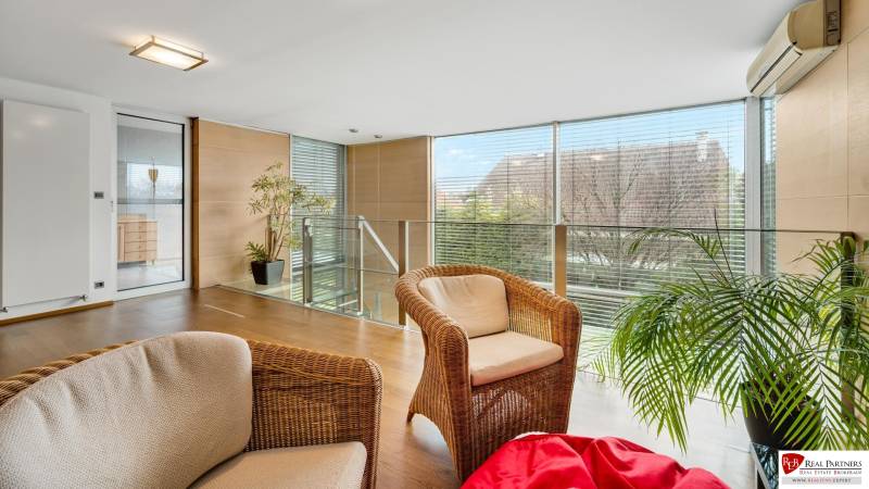 Predaj moderná 5 izbová vila, 265 m2, pozemok 953 m2, bazén,BA II. - Priestranná miestnosť s prútenými kreslami, drevenou podlahou a rastlinou na ulici Imelová.